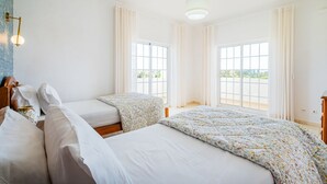 Une chambre d’hôtel avec deux lits, de grandes fenêtres et un luminaire au plafond.