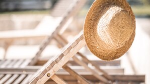 Una hilera de sillones de madera con un sombrero de paja tejido sobre uno.