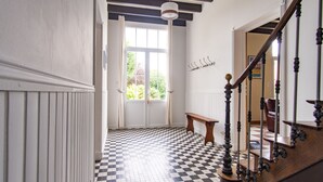 Un pasillo con piso a cuadros, un banco de madera y una escalera con barandilla ornamentada.