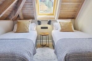 A room with two beds, a small table, and a window.
