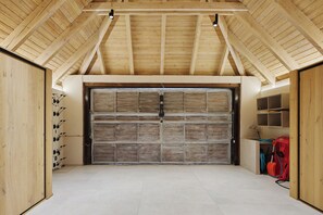 A garage with a large wooden door, a tiled floor, and a sloped ceiling. - Casa Garona by FeelFree Rentals (Vielha)