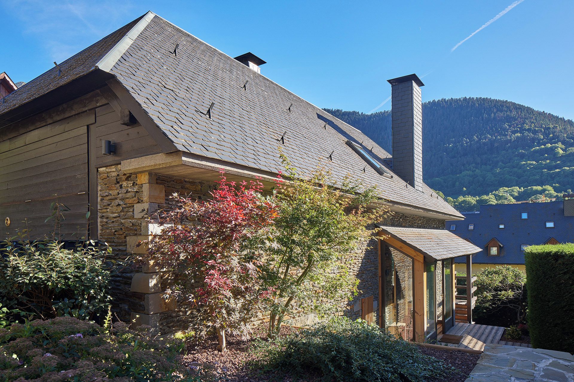 A house with a sloped roof, stone walls, and a chimney.