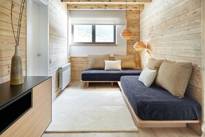 Una stanza accogliente in stile baita, con un letto a scomparsa, un tavolino e un termosifone.