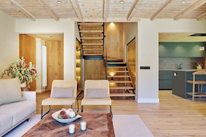 A modern interior with a wooden staircase, wicker furniture, and a kitchen area.