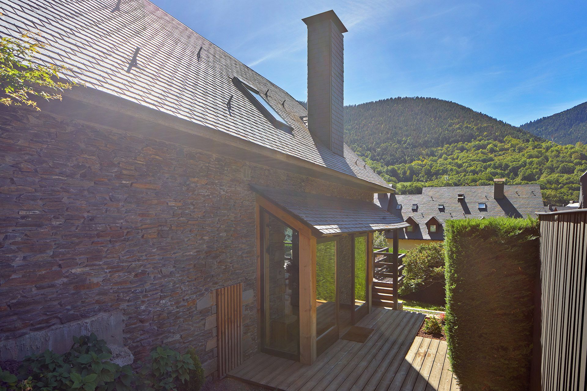 Un bâtiment de style rustique, doté d’une façade en pierre, d’une terrasse en bois et d’une cheminée.
