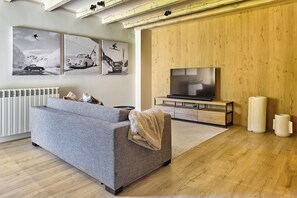 A modern living room with a sofa, a flat-screen TV, and wall-mounted artwork.