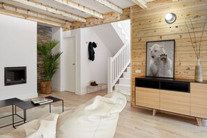 Una sala de estar moderna con chimenea, una escalera y un cuadro grande de un oso polar.