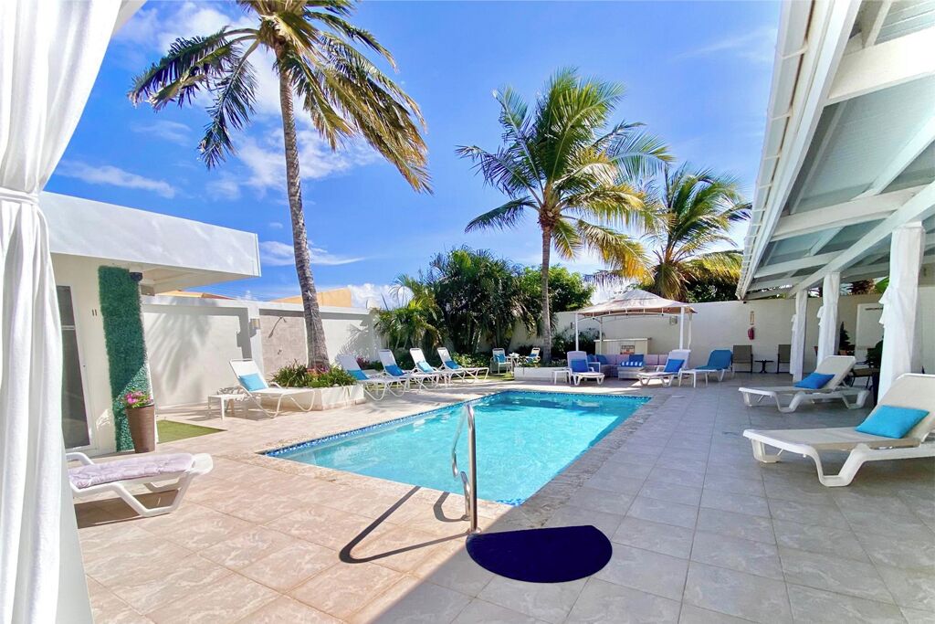 A pool area with lounge chairs and palm trees.
