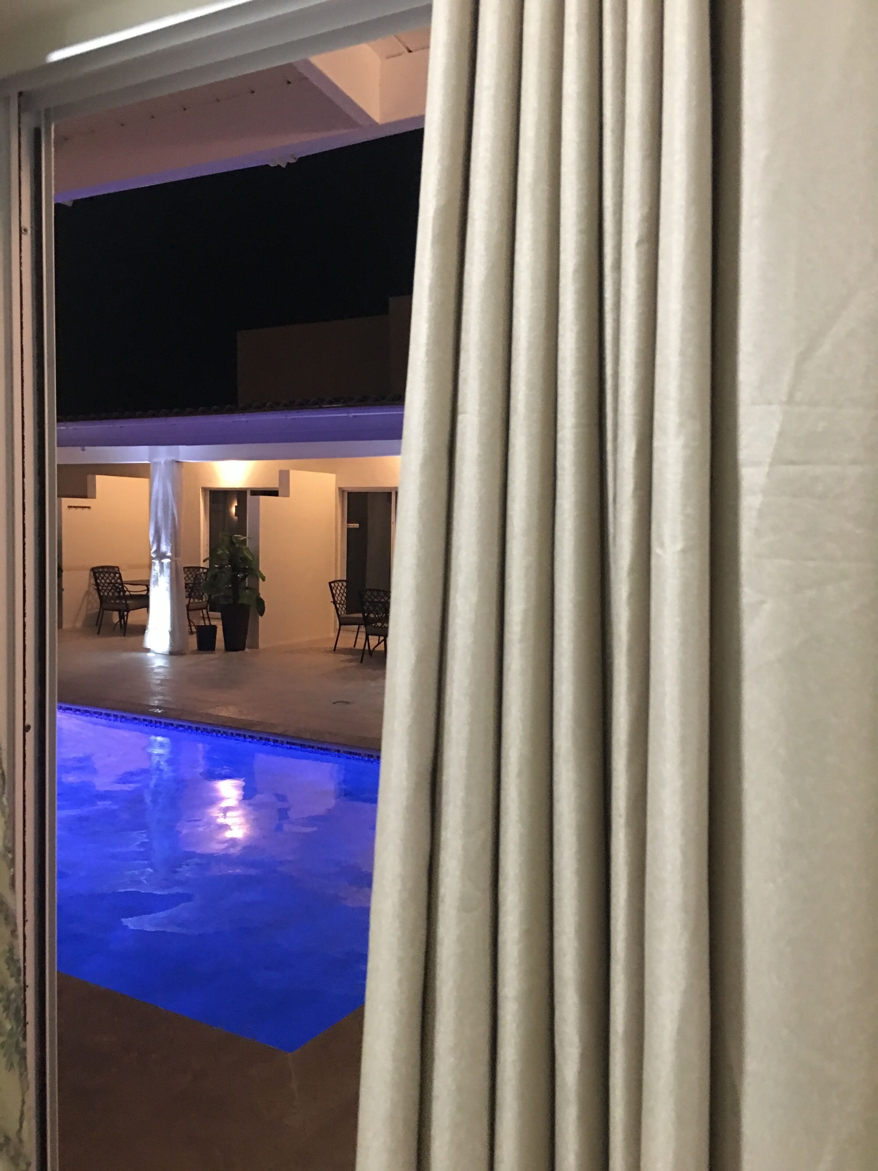 An outdoor pool area with a covered seating area and potted plants.