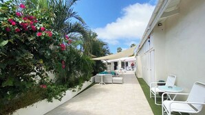 A pool area with white lounge chairs, a small pool, and a covered seating area. - Yoyita Suites Aruba (Noord)