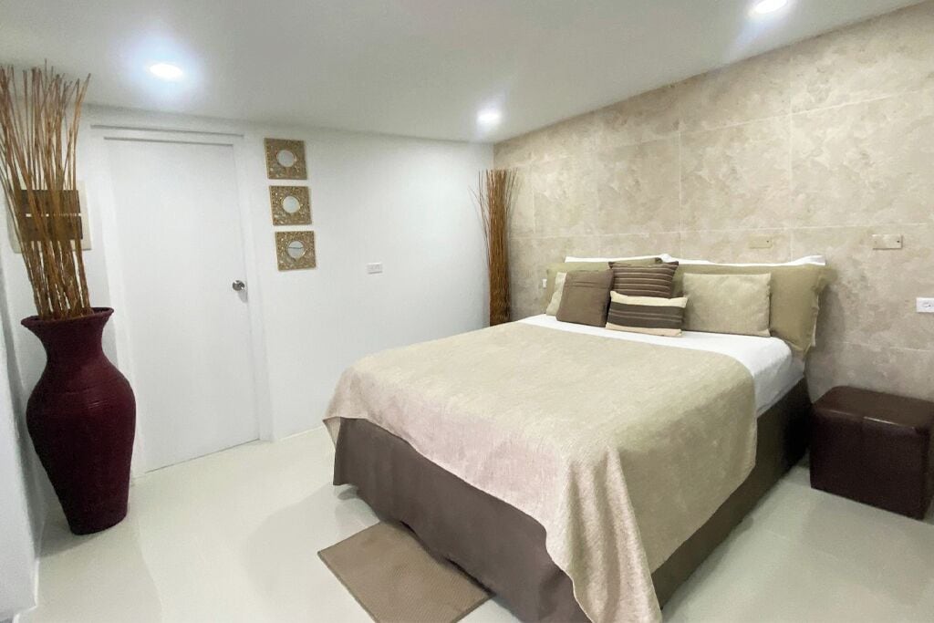 Un dormitorio con una cama, un florero y una puerta.