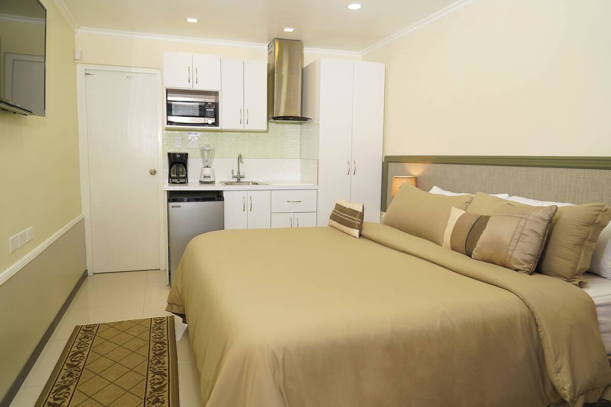 Een kleine hotelkamer met een bed, een kitchenette en een badkamer.