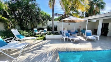 Una piscina al aire libre, sillones reclinables de piscina