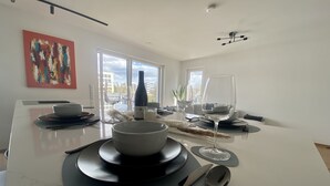 A modern dining area with a central island, a wine bottle, and glasses on a table. - 2BD high end Apt. 134m2 in Strassen (Strassen)