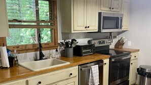 Una cocina con piso de madera, armarios blancos, microondas, tostadora y un lavamanos.