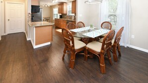 A spacious kitchen with wooden cabinets, a central island, and a dining area with a glass table and chairs. - 3BR Walk to the Beach House in Surfside Beach! Looney Dunes (Surfside Beach)