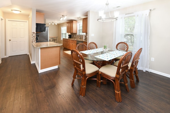 A spacious kitchen with wooden cabinets, a central island, and a dining area with a glass table and chairs.