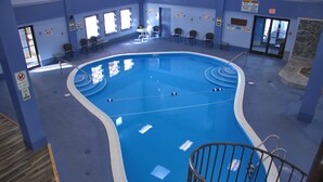 An indoor swimming pool with a curved design, surrounded by chairs and a small table. - 2208  Hot tub, sauna & more resort amenities - Paradise in the Mountains (Beech Mountain)