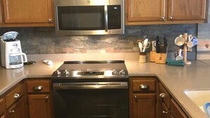 A kitchen with wooden cabinets, a stainless steel microwave, a stove, and a coffee maker. - 2208  Hot tub, sauna & more resort amenities - Paradise in the Mountains (Beech Mountain)