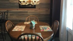 A dining area with a wooden wall, a chandelier, and a small house model on the table. - 2208  Hot tub, sauna & more resort amenities - Paradise in the Mountains (Beech Mountain)