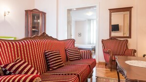 A room with striped sofas, a wooden cabinet, a dining table, and a mirror on the wall. - Apartments Dobrinjska (Београд)