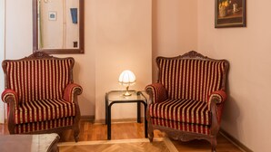 A room with two ornate armchairs, a small table with a lamp, a mirror, and a framed painting on the wall. - Apartments Dobrinjska (Београд)