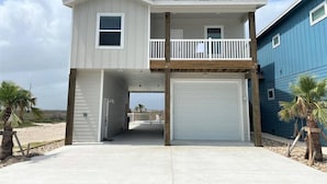 Une maison à deux étages avec un balcon, un garage et une vue sur la plage.