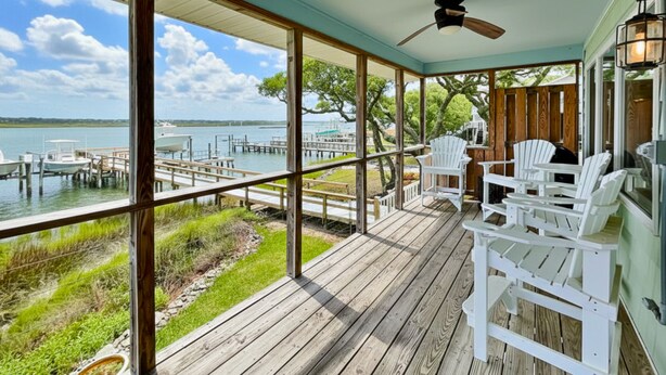 A wooden deck with white Adirondack chairs overlooking a marina with boats. - The Hydeaway | Pet Friendly, Soundfront with Dock! (Topsail Beach)