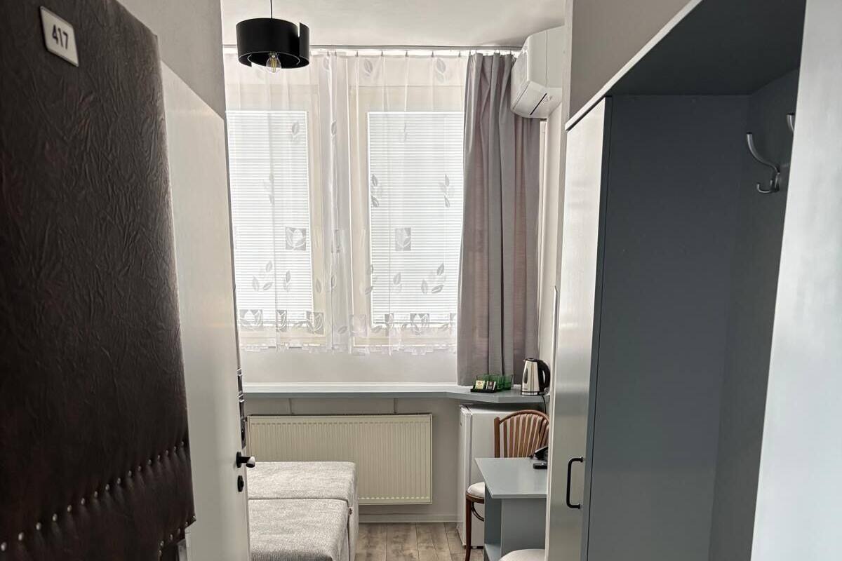 A compact room with a bed, a small table, a chair, and a wardrobe.