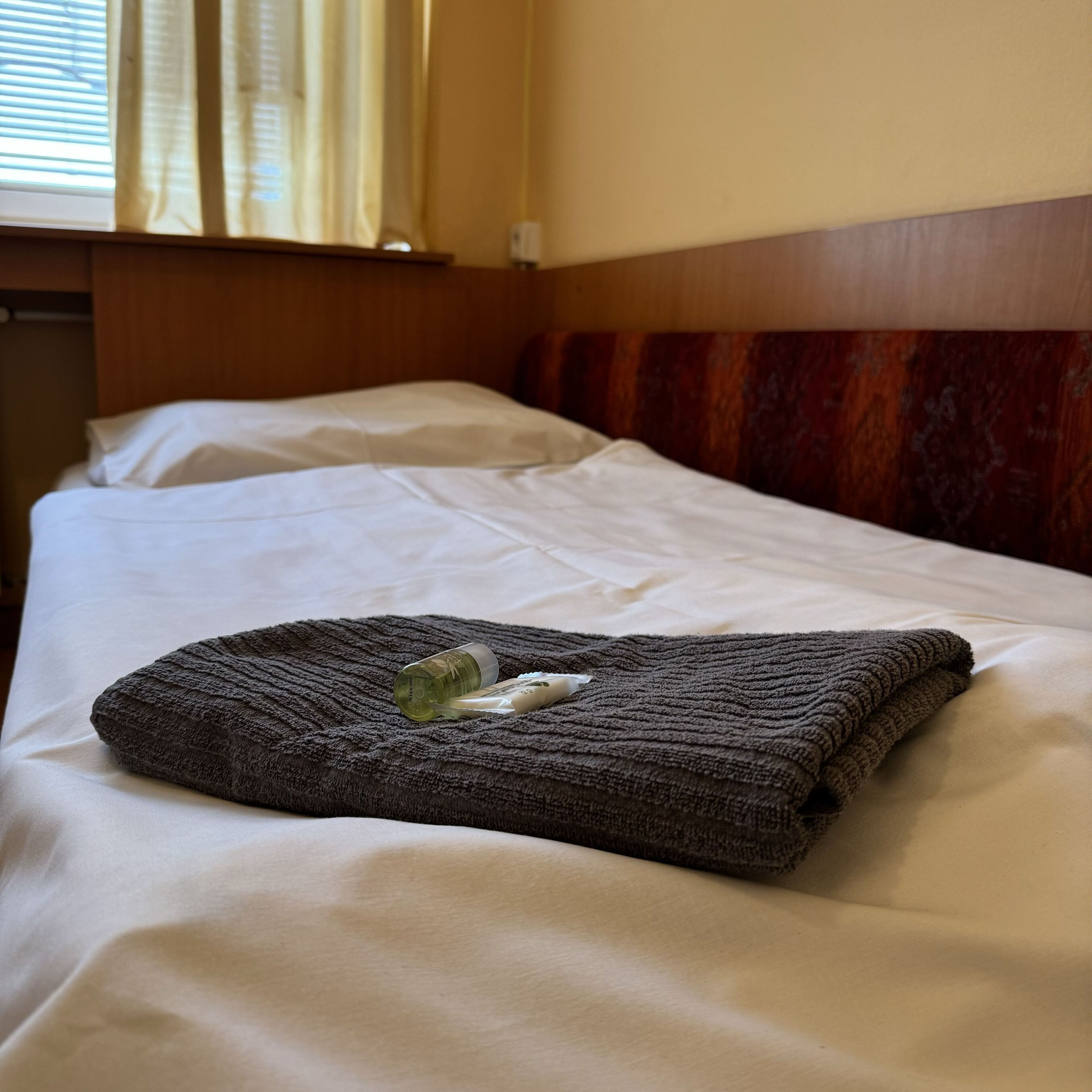 Una cama bien hecha con una manta doblada y una botella de agua encima.