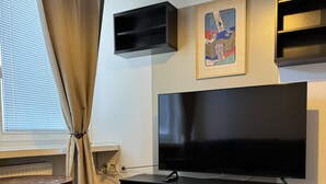Una sala de estar moderna con un televisor de pantalla plana, un mueble de madera para entretenimiento y una ventana con persianas.