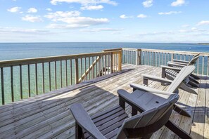 Um deck de madeira com guarda-corpo, com vista para a água.