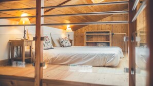 A cozy attic bedroom with a wooden ceiling, a bed with white bedding, and two bedside lamps. - Le Serre d'Or, large apartment at the foot of the slopes (Saint-Chaffrey)
