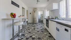 Una cocina moderna con piso estampado, muebles blancos, un refrigerador de acero inoxidable y un taburete de bar.