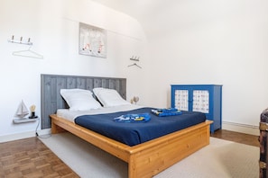 A bedroom with a wooden bed, white pillows, a blue blanket, and a blue wardrobe. - Le Roulis - Maison familiale avec jardin (Saint-Cast-le-Guildo)