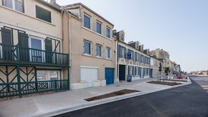 A row of townhouses with balconies, a clear sky, and a sidewalk. - Callisto - Appartement Vue Mer (Luc-sur-Mer)