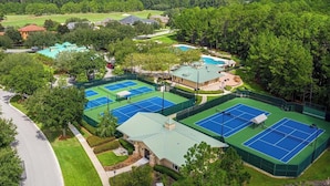 Ein Tennisplatzkomplex mit mehreren Plätzen, einem Pool und umliegender Bepflanzung.