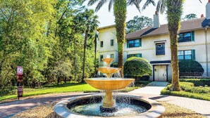A multi-tiered fountain in a circular stone basin surrounded by pebbles, with a building in the background. - 2-BR large private fenced courtyard-close to entrance & pool / hot tub (Saint Augustine)