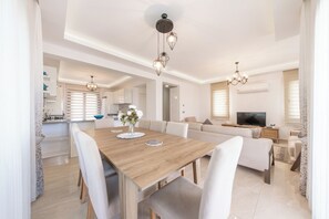 A modern living space with a dining area, sofa set, and a television.