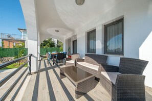 A balcony with wicker furniture, a table, and chairs.
