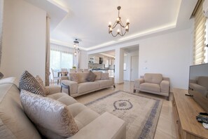 A spacious living area with a sofa set, a coffee table, and a television.
