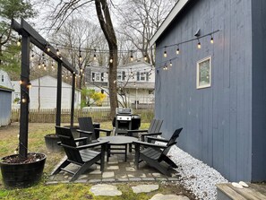 Eine Terrasse mit Tisch, Stühlen, einem Grill und Lichterketten.