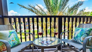 Un balcon avec deux chaises, une table et deux verres à vin.