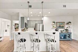 A modern kitchen with white cabinetry, stainless steel appliances, and pendant lighting. - Private balcony-King bed-full kitchen-W/D-community pool & hot tub (St. Augustine)