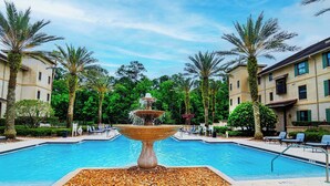 Uima-allas, jonka keskellä on suihkulähde, ja jonka ympärillä on palmuja sekä aurinkotuoleja.