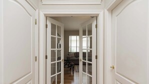 A hallway with white doors leading to a living area with a sofa and a coffee table. - Private home-Large screened lanai-BBQ- sleeps 8-easy walk to pool! (Saint Augustine)
