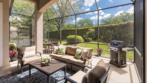 A covered patio with a sofa, chairs, a table, and a grill. - Private home-Large screened lanai-BBQ- sleeps 8-easy walk to pool! (Saint Augustine)