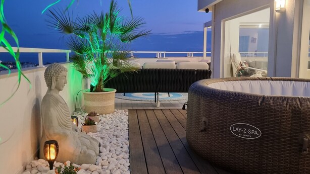 Terraza en la azotea con jacuzzi, zona de estar y plantas decorativas.