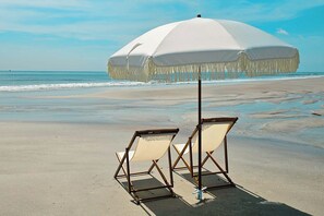 A beach with two beach chairs and a large white umbrella. - King Suite w/ kitchenette & full size fridge -55 in TV cable -pool & hot tub! (St. Augustine)