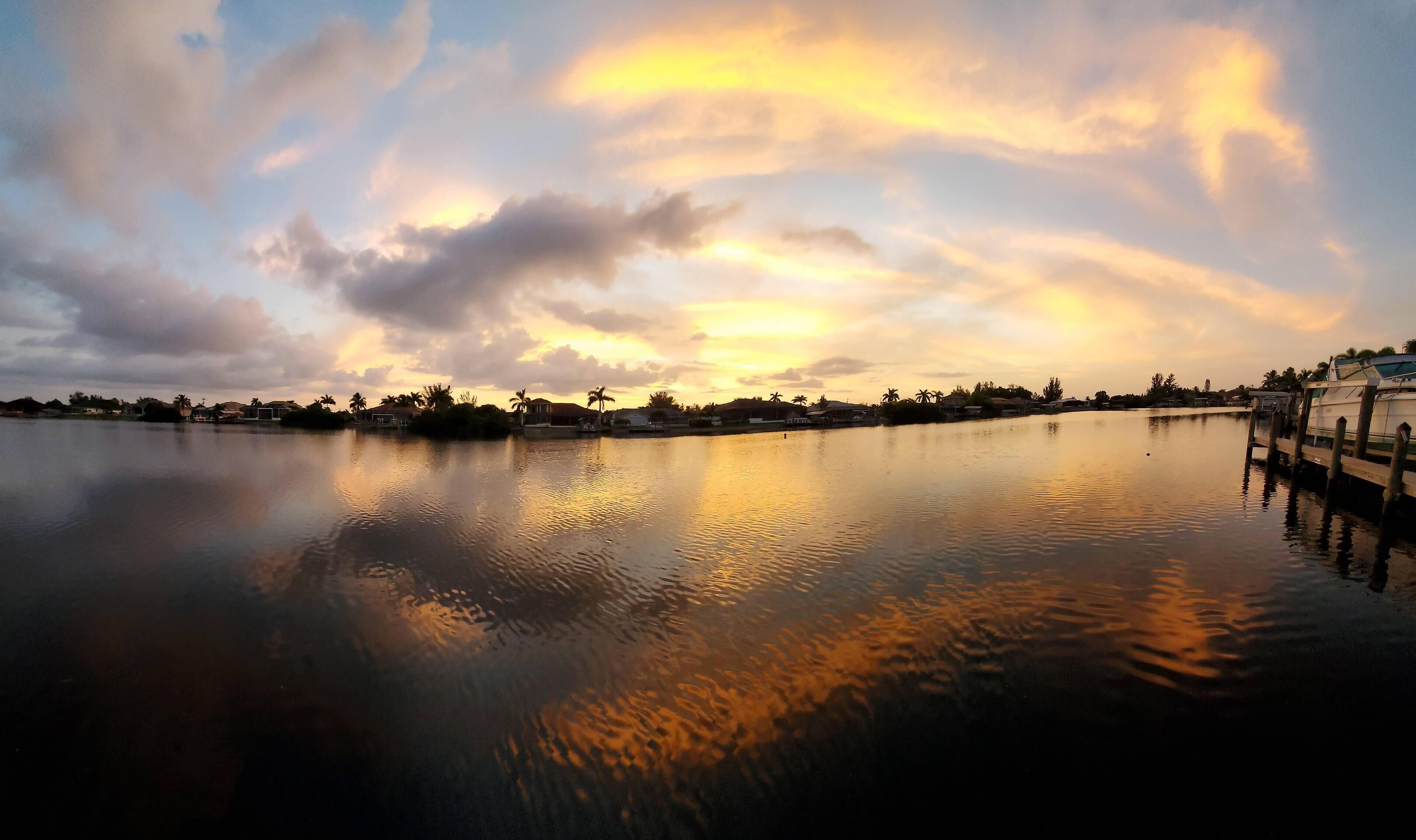 Un lago tranquilo al atardecer con un muelle a la derecha.